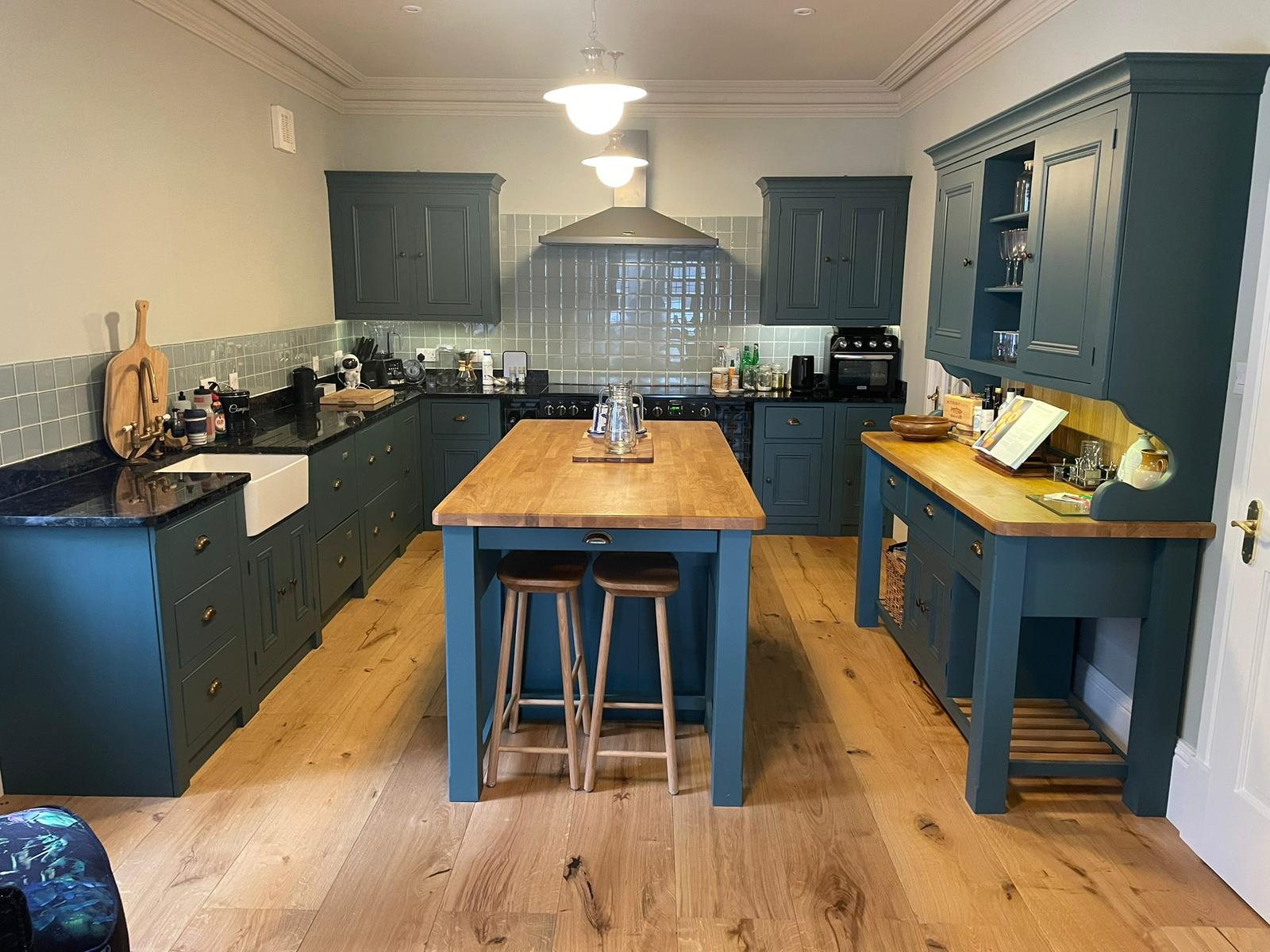 After - Renovated kitchen with dark teal cabinets and oak floor
